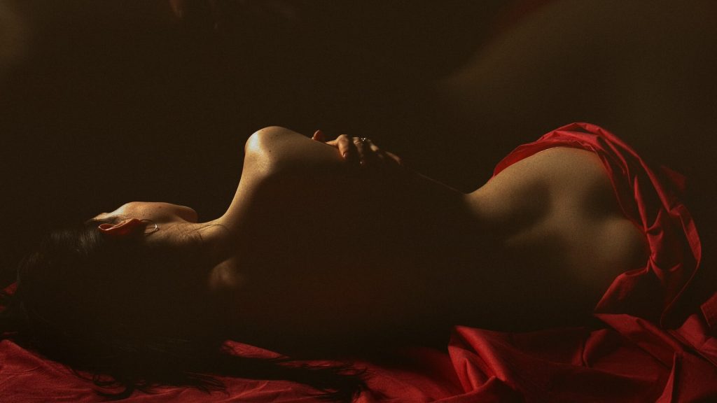 A photo of a girl naked in a bed with her back to the camera